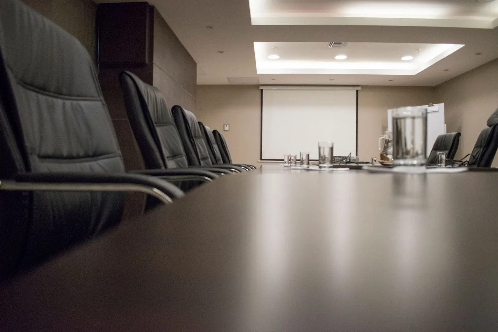 An empty boardroom with leather chairs along a long polished table