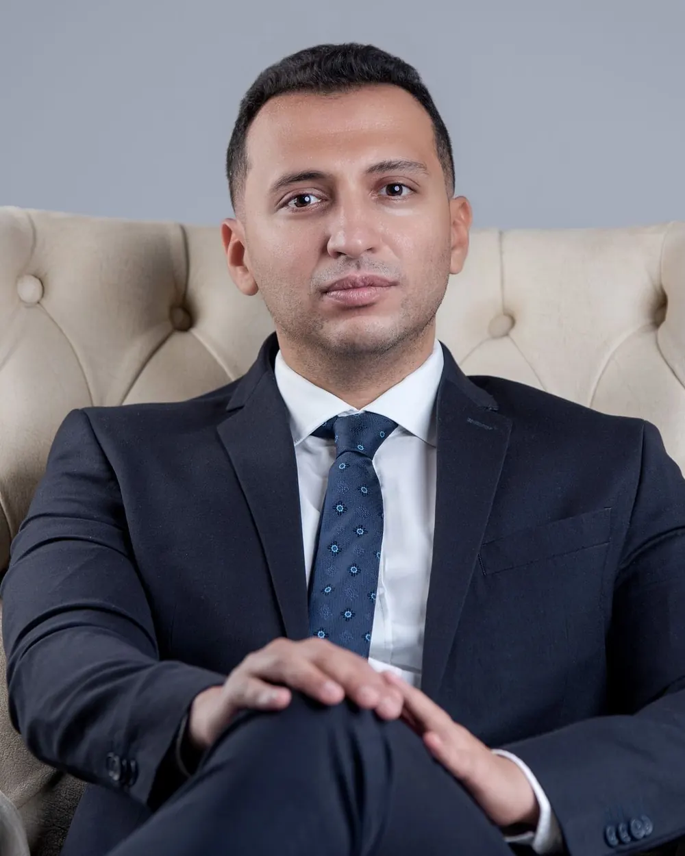 A professional in a navy suit seated in an armchair